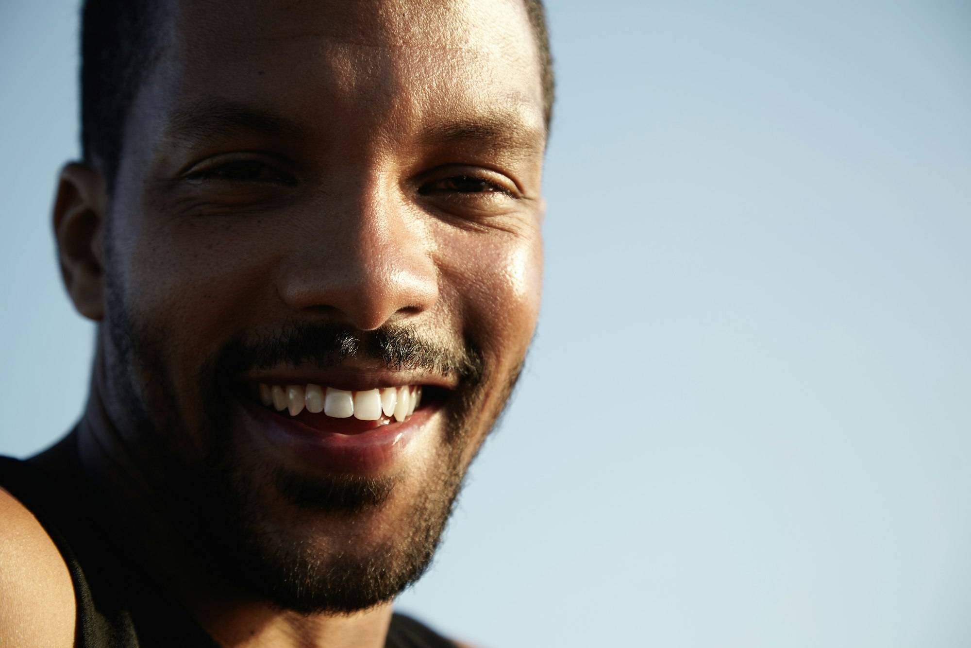 Close up shot of attractive African student with happy look, smiling, laughing, having fun during ni